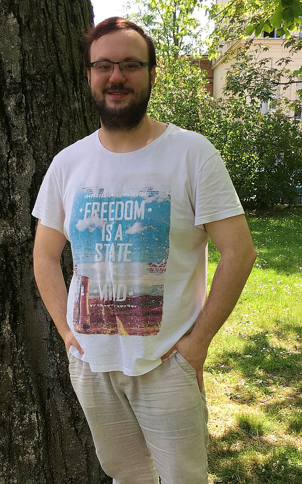 Robert Wolfsteller steht vor einem Baum in einem Garten.